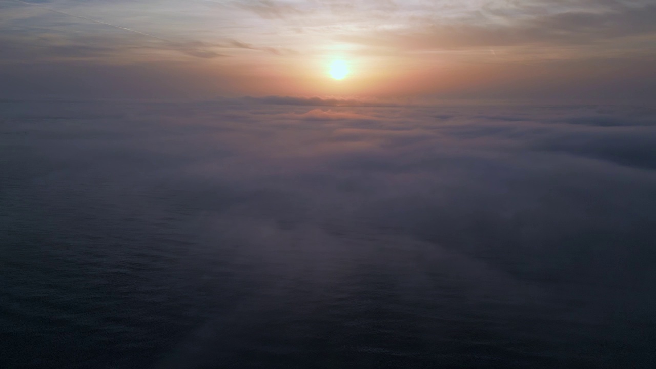 鸟瞰图，日出的海面上笼罩着晨雾和早晨的阳光视频素材