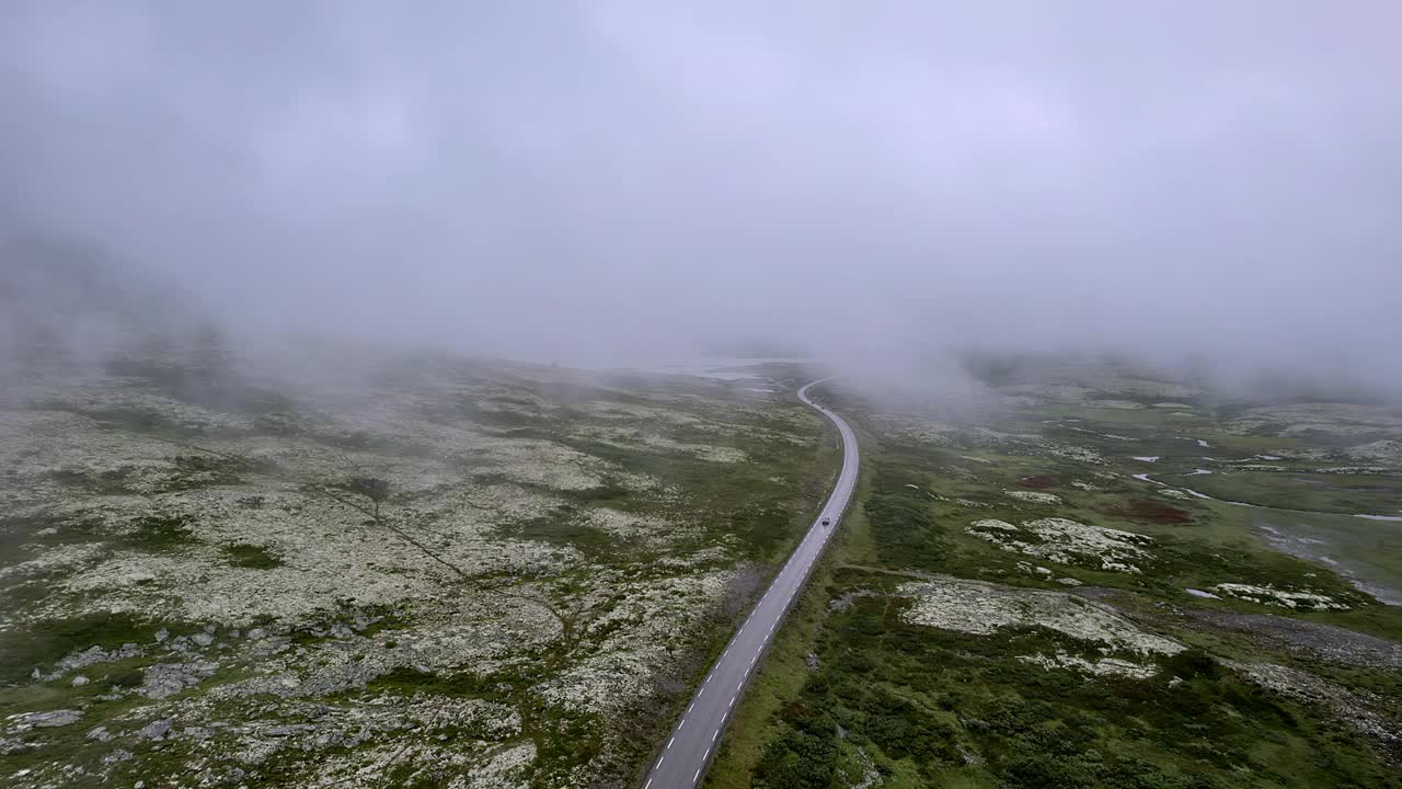 鸟瞰在雾天行驶在蜿蜒山路上的汽车视频素材