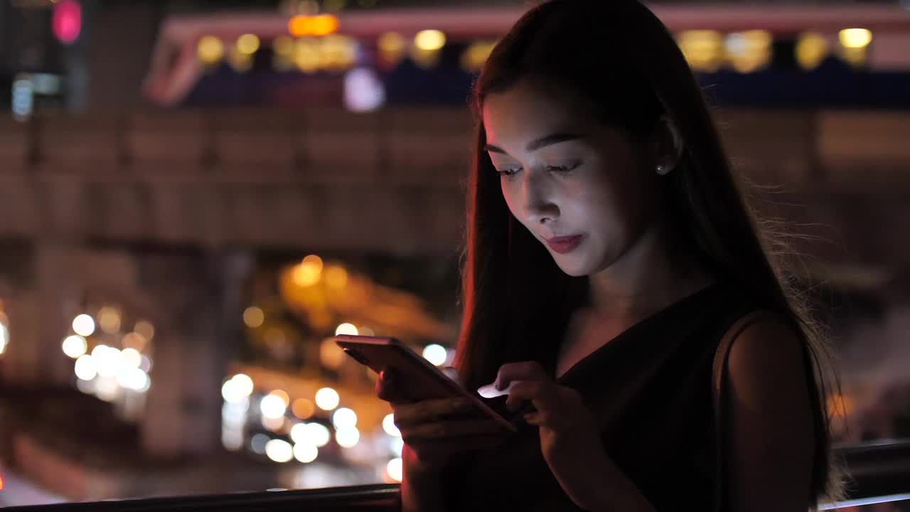 亚洲女性在晚上用手机搜索视频素材