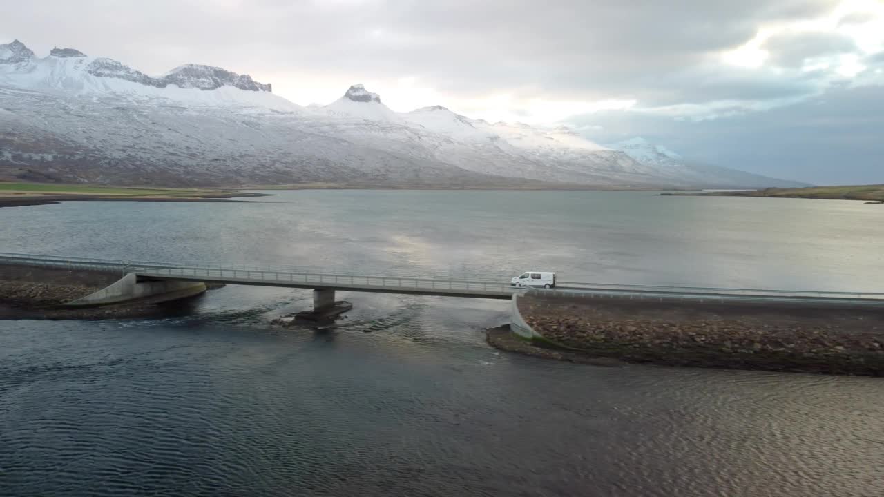 无人机在冰岛拍摄了一幅美丽的风景，一辆汽车在海上的道路上行驶，背景是山脉。视频素材