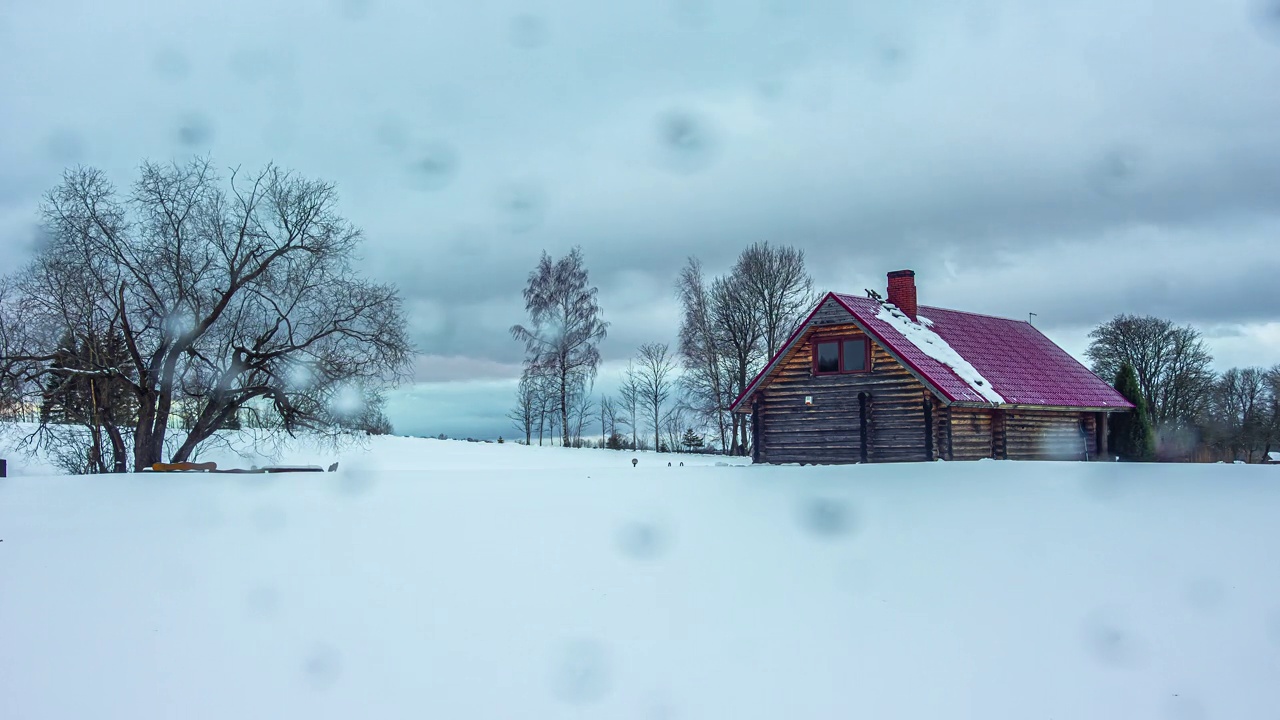 冬天，在村庄里看到一间小屋，周围是摇曳的树木和一层雪，这真是令人着迷。它描绘了一幅令人叹为观止的景象。视频素材