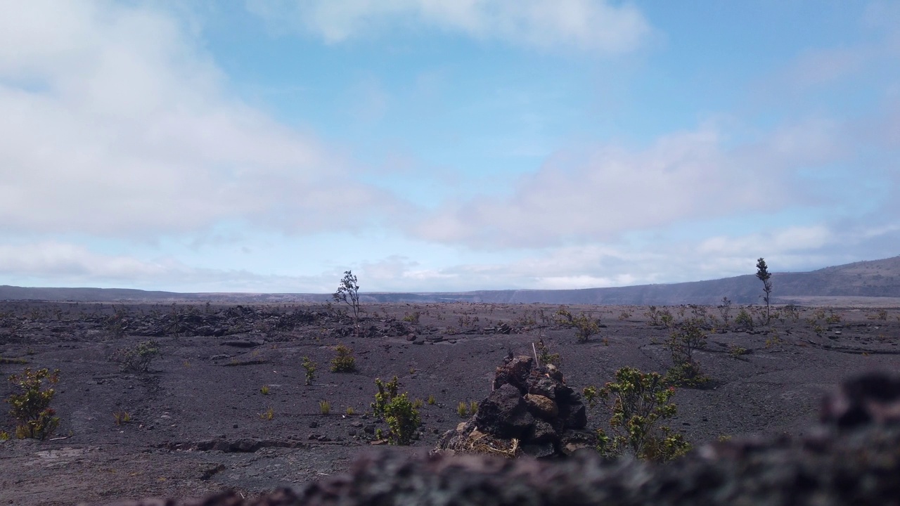 从基拉韦厄火山口边缘拍摄的万向节宽摄影车，在夏威夷岛上的前景是干燥的熔岩岩石。4K 60 FPS慢动作视频素材