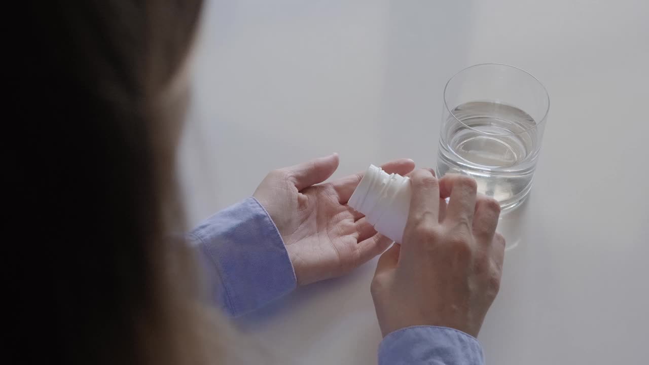 一个接一个地服用各种药片和药片的妇女。后视图视频素材