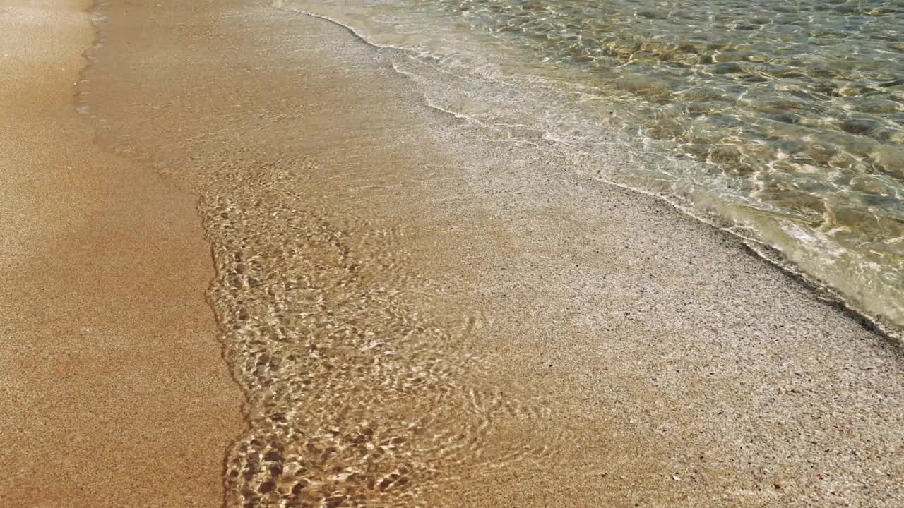 海浪拍打着海滩，一派宁静的白天景象。温柔的海浪抚摸着海滩，展示着大自然的韵律。海浪与沙滩沙滩相遇时捕捉到的海滩宁静。视频素材