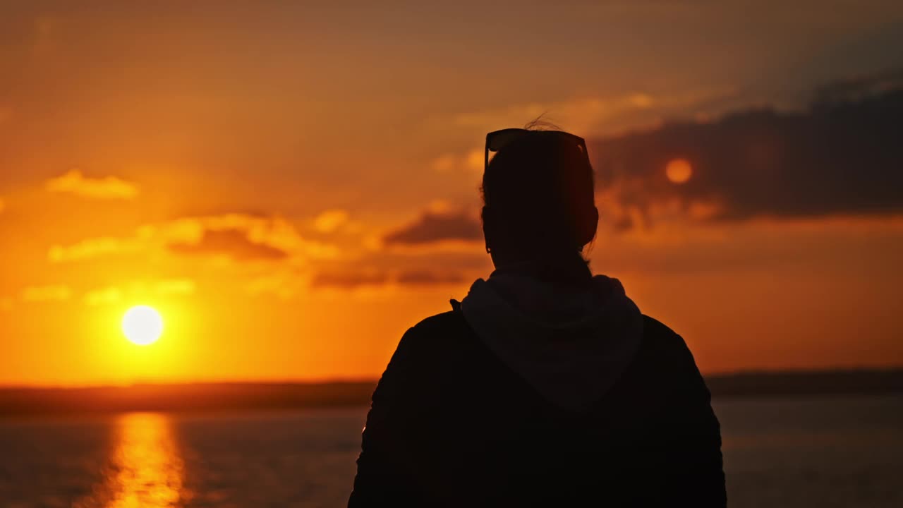 一个年轻女子的剪影举起她的双手对抗夕阳的慢动作视频素材