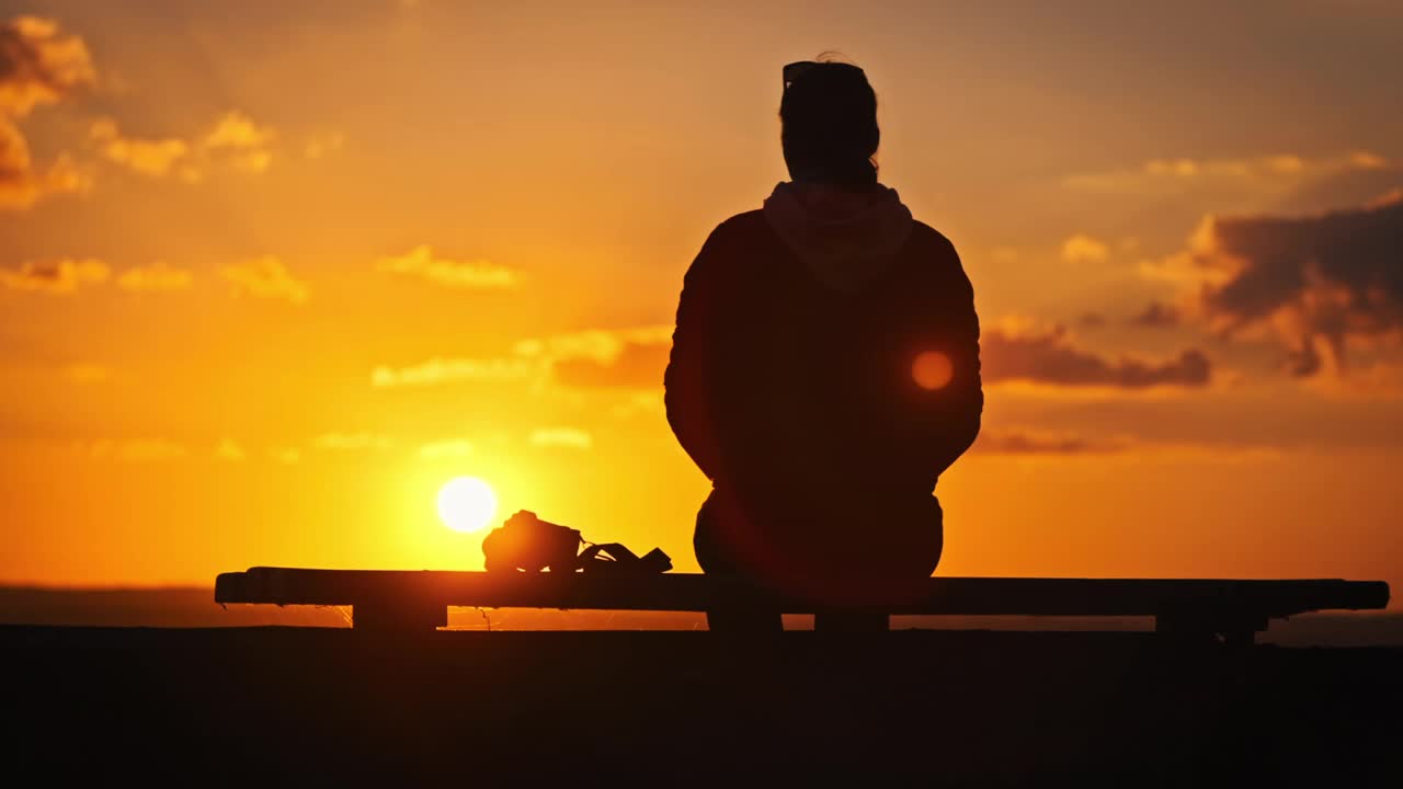 一个年轻女子的剪影举起她的双手对抗夕阳的慢动作视频素材