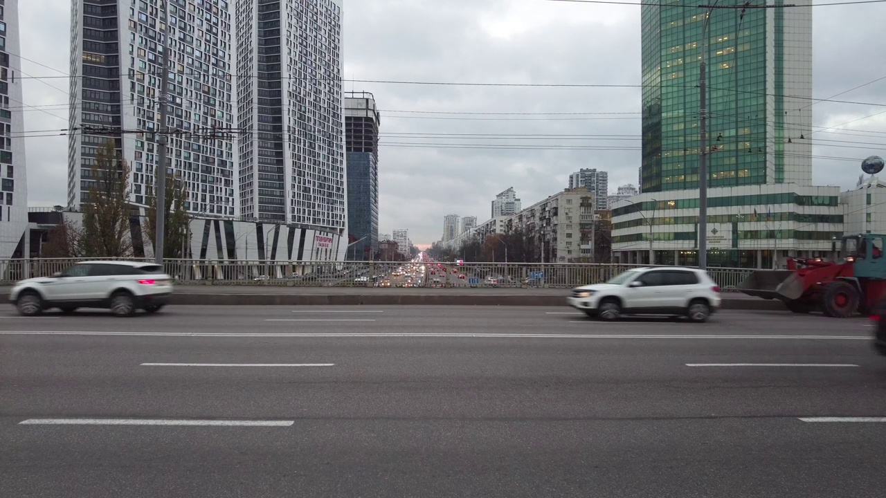 汽车沿着道路行驶，背景是城市的高层建筑视频素材