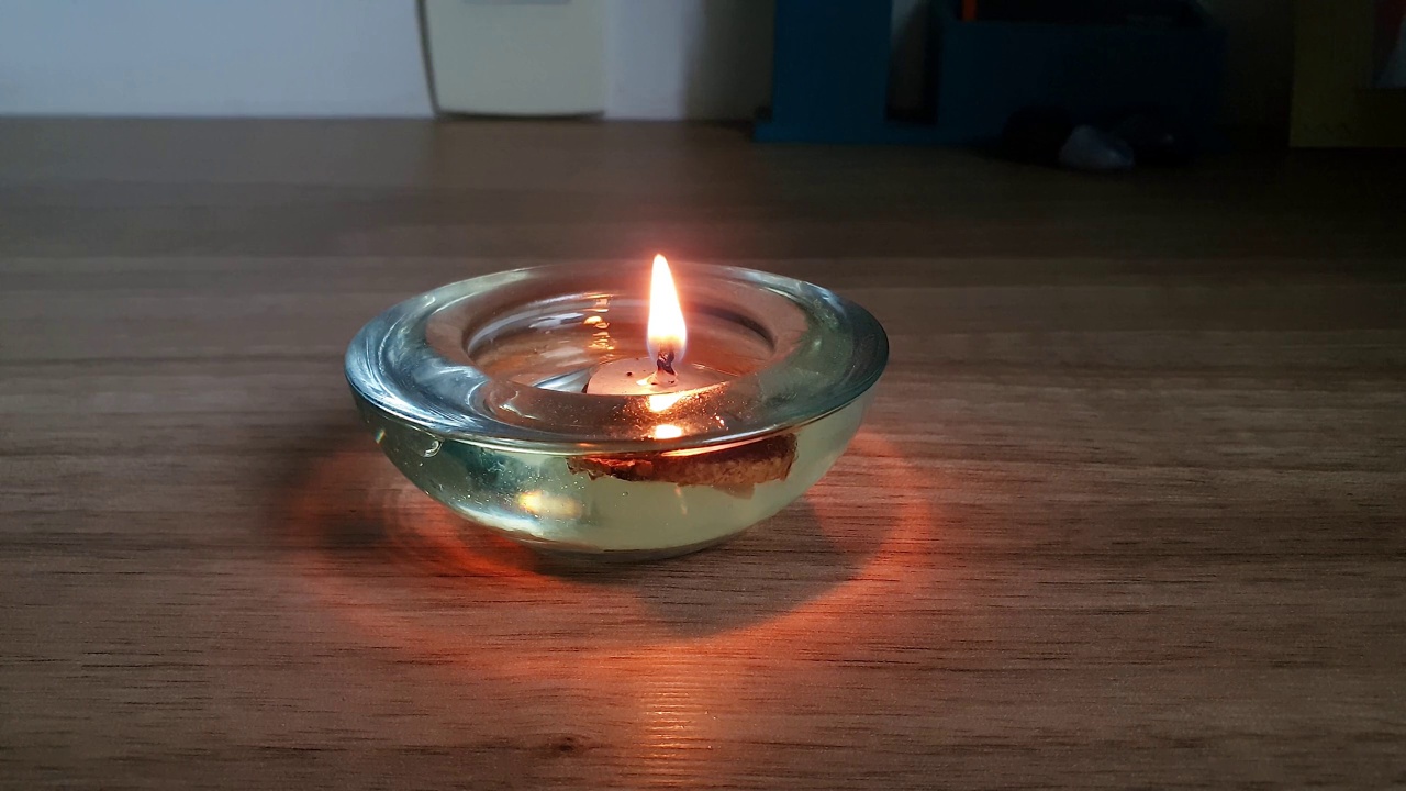 一个小蜡烛在油中燃烧的特写，被聚焦。视频素材
