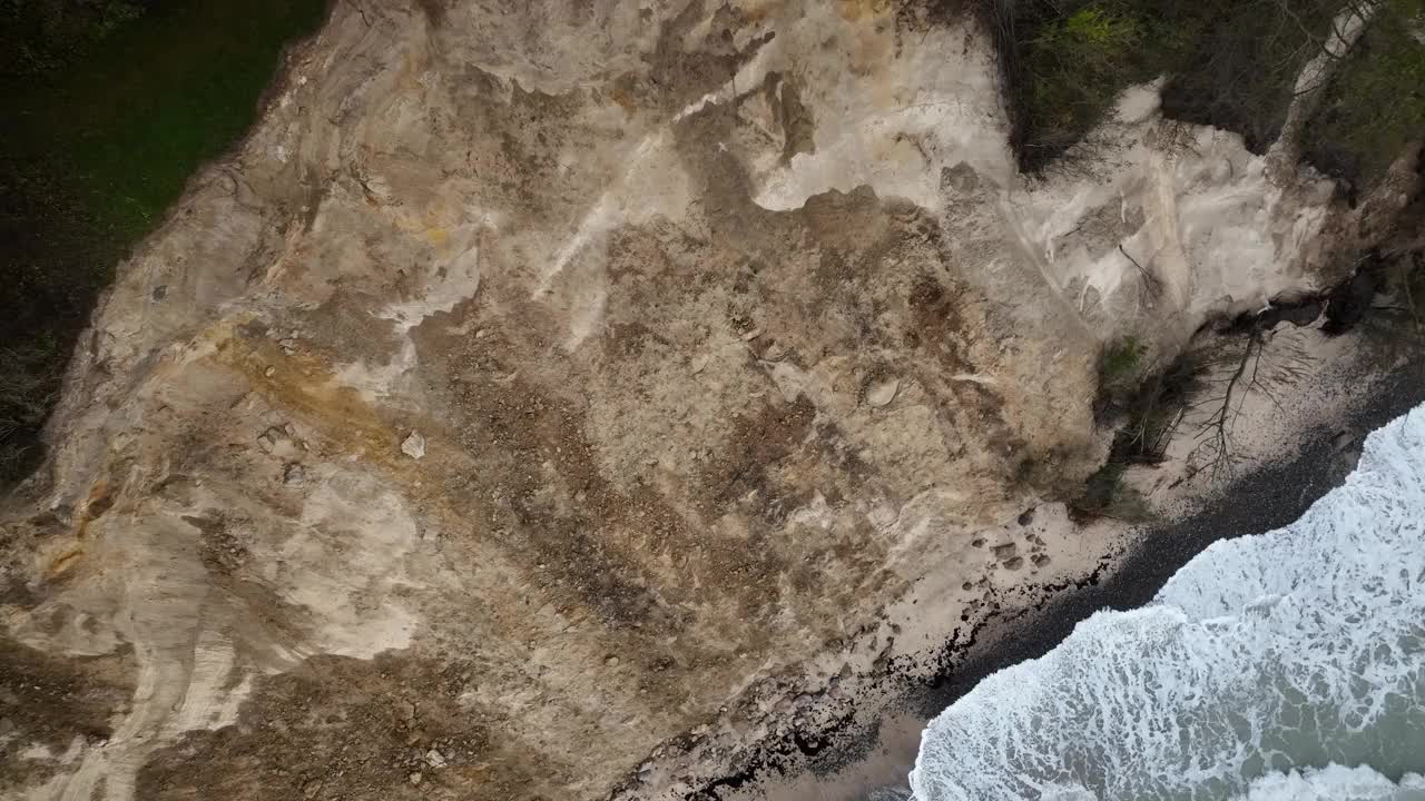 风暴过后，沙质悬崖上的岩石破碎，倒下的树木被海浪拍打着，悬崖顶上矗立着灯塔。灯塔如同跨品牌的火在Møn的悬崖边上视频素材