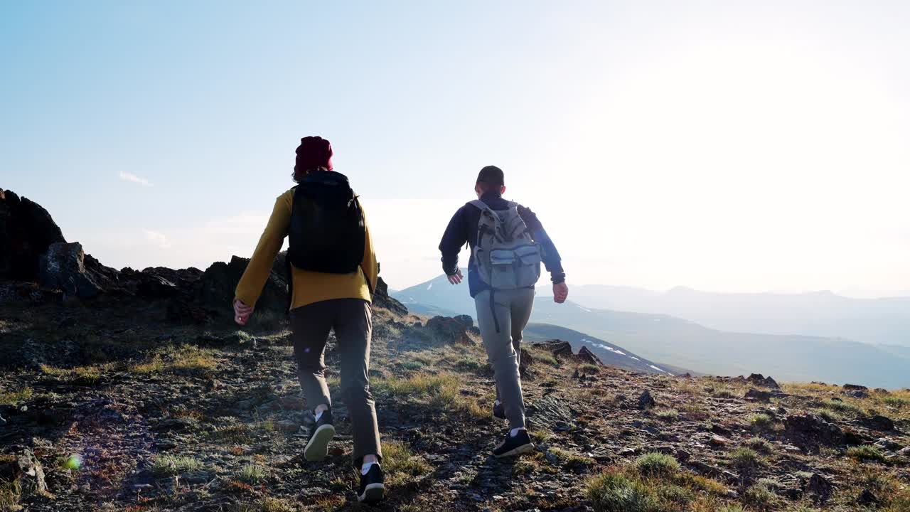 两个年轻的旅行者到达悬崖顶峰，在山顶上欣赏风景视频素材