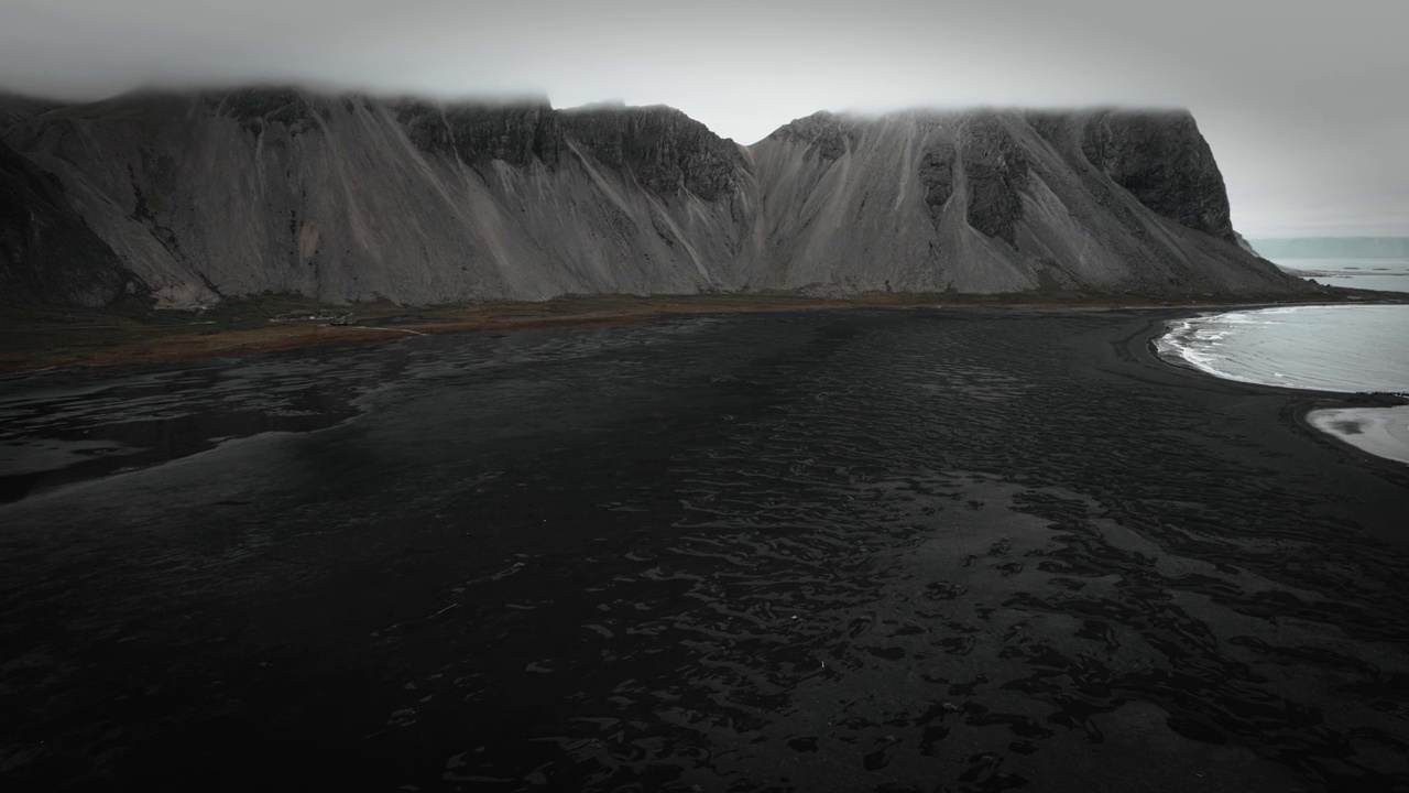 空中黑色的沙滩沙滩，黑色的火山山脉，远处的vestrahorn，阴暗阴沉的冰岛风光视频素材