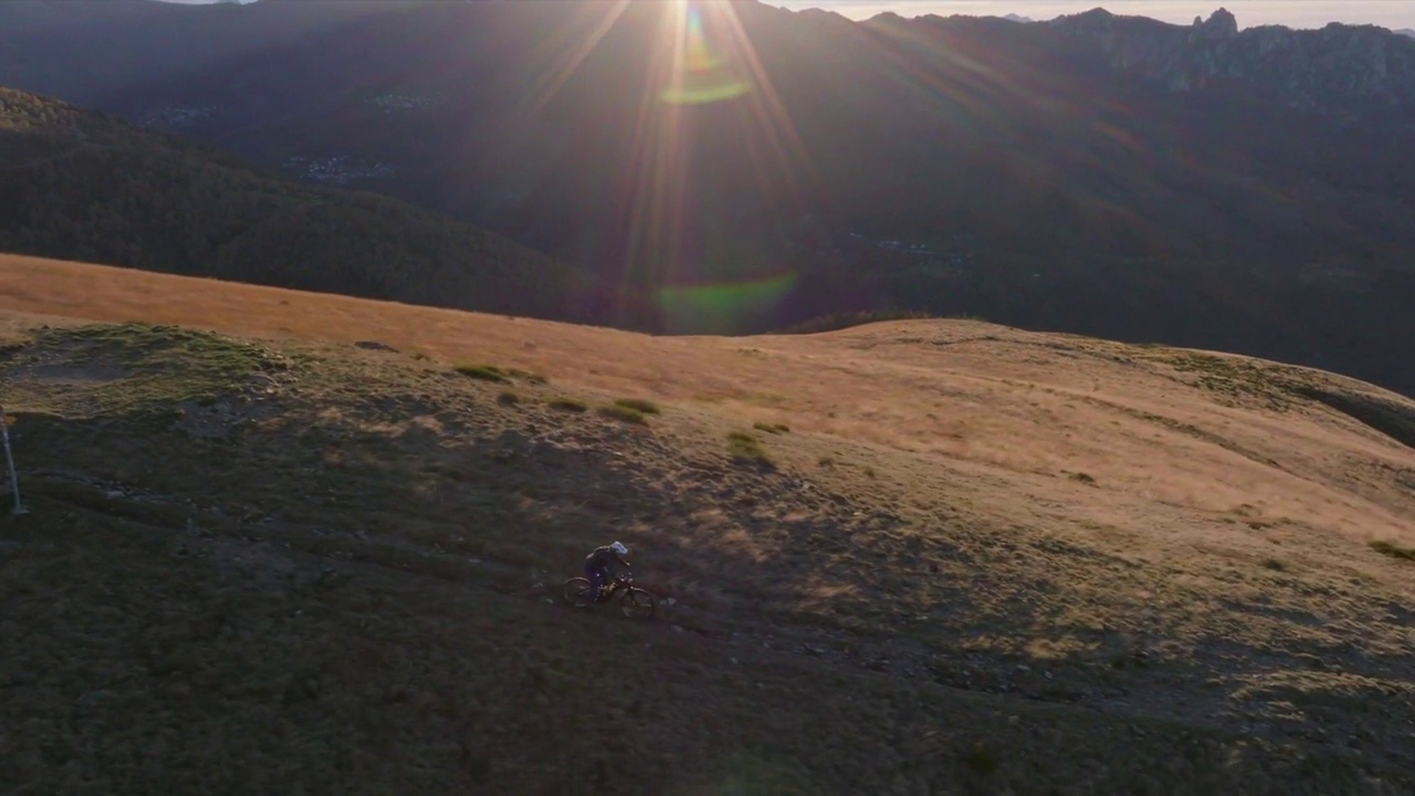 骑山地自行车的人在日出时沿着山脊的单轨骑行，远处的城市景色视频素材