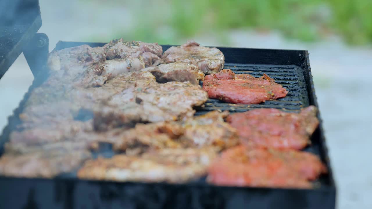 在户外烧烤。特写美味的烤肉牛排。夏日野餐的概念，食物，味道，派对，烹饪。烧烤烟和火焰，烤肉在火上。视频素材