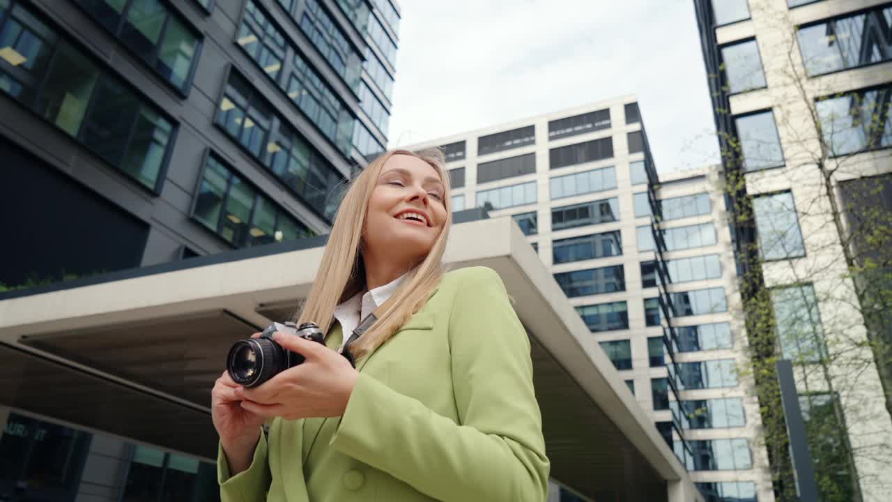 快乐的女街头摄影师拍摄现代城市的户外建筑视频素材