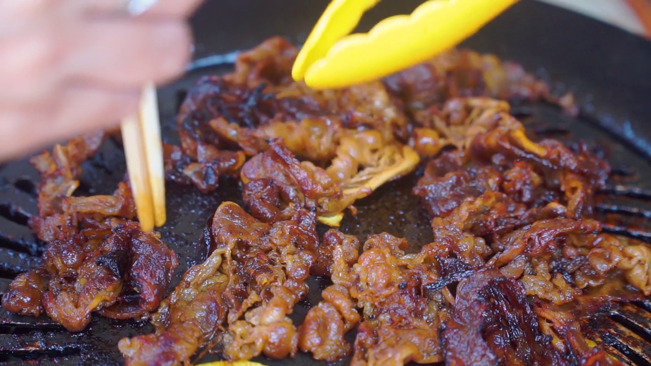 用食物钳在烤盘上烤烤肉的特写镜头视频素材