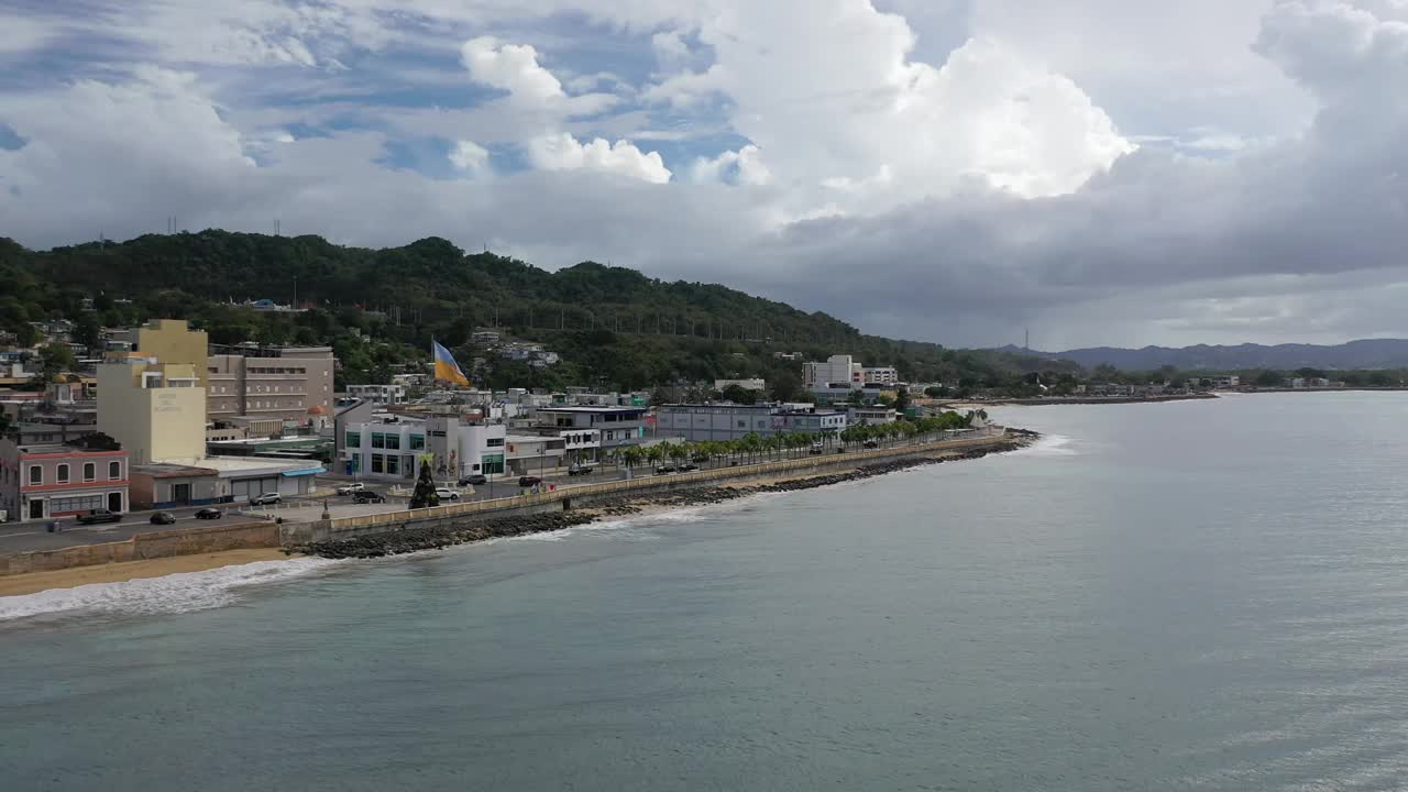 无人机拍摄的汽车在波多黎各阿瓜迪拉沿海道路和海滨建筑上行驶的画面视频素材