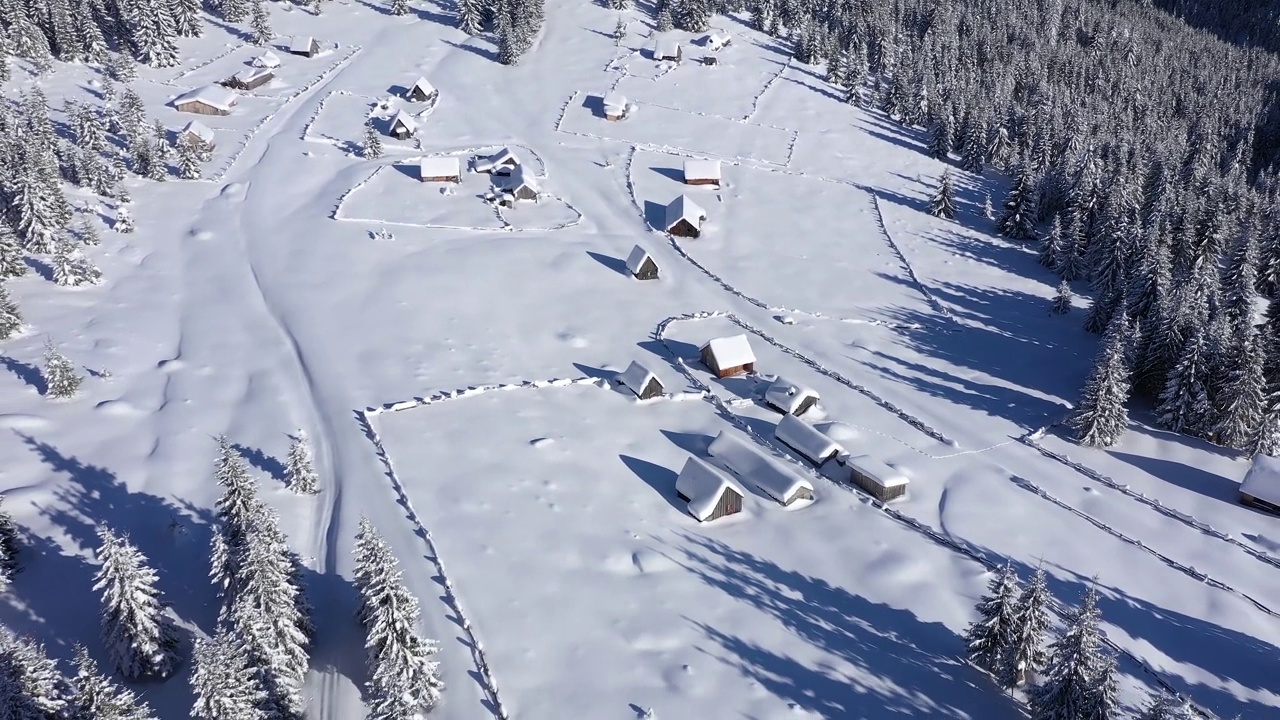 无人机航拍积雪覆盖的偏远村庄，山间宅基地。埋在雪下的房屋视频素材