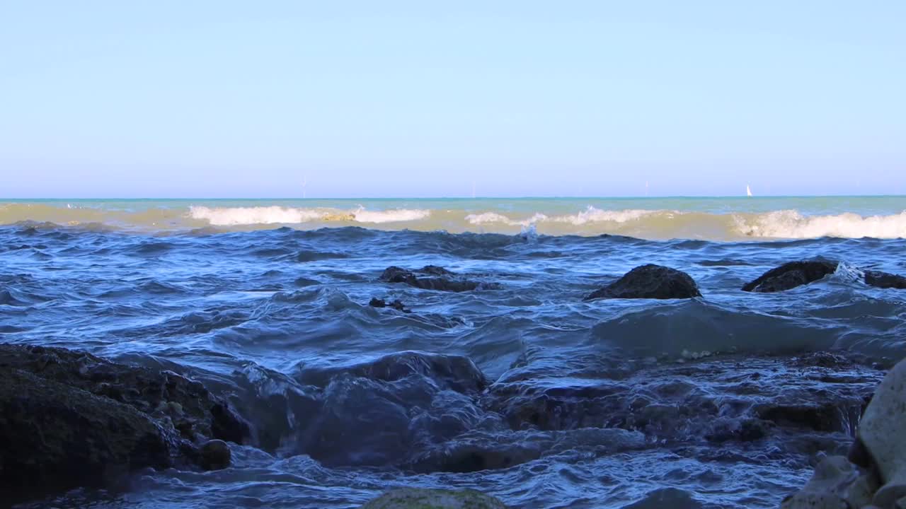 从低角度看，破碎的海浪拍打着海滩上的岩石视频下载