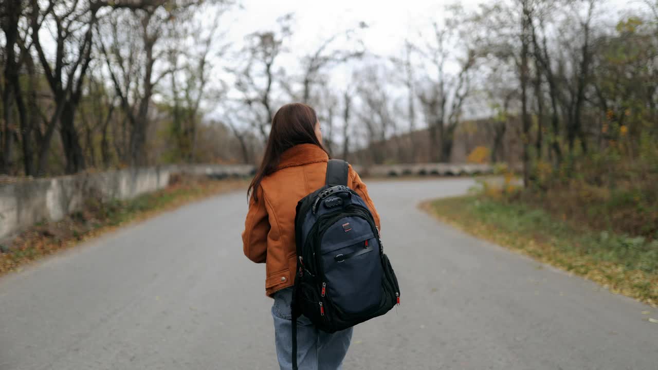 年轻的女性旅行者带着相机，拍摄鸟类，动物，风景。一名女游客背着背包，在秋天独自旅行时用相机拍照视频下载