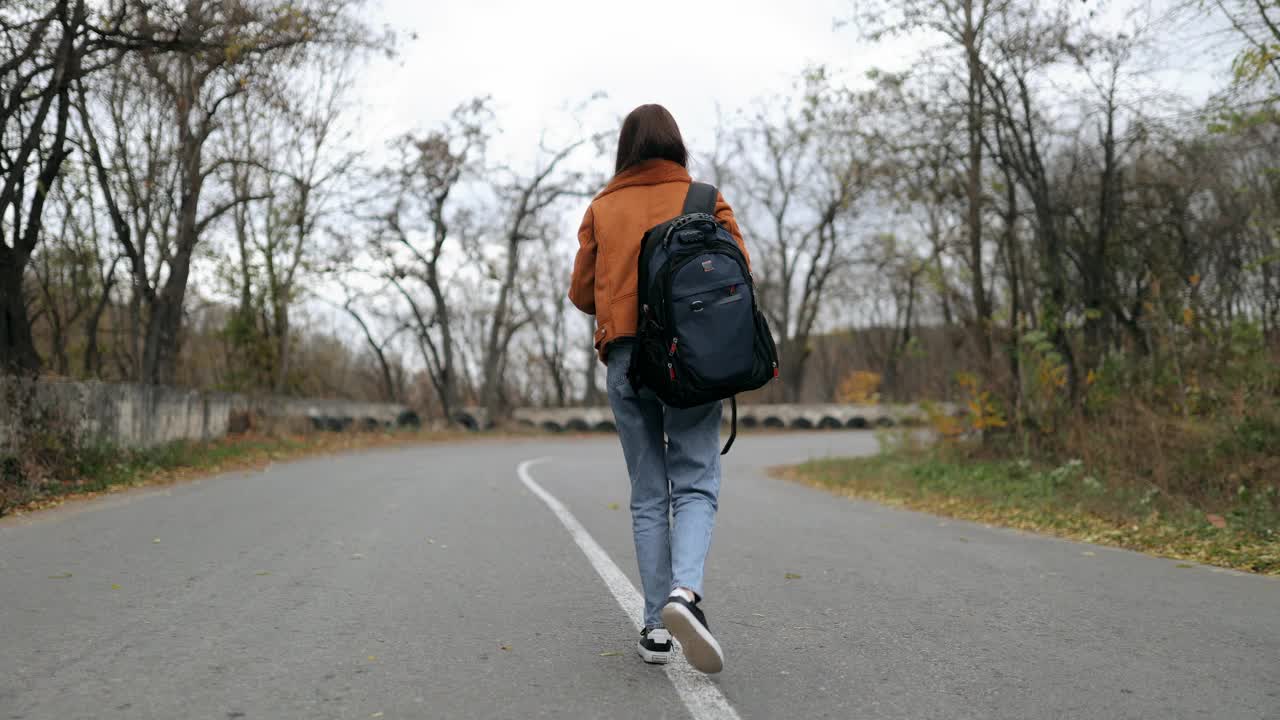 漂亮的年轻女游客带着公文包走在乡间小路上看大自然。高品质4k视频视频素材