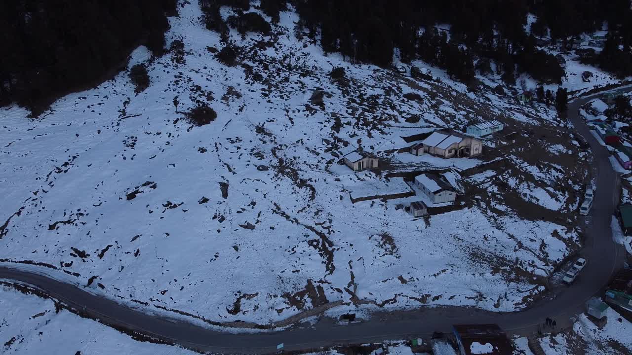 无人机拍摄的山腰村庄被雪覆盖的绿色森林视频素材