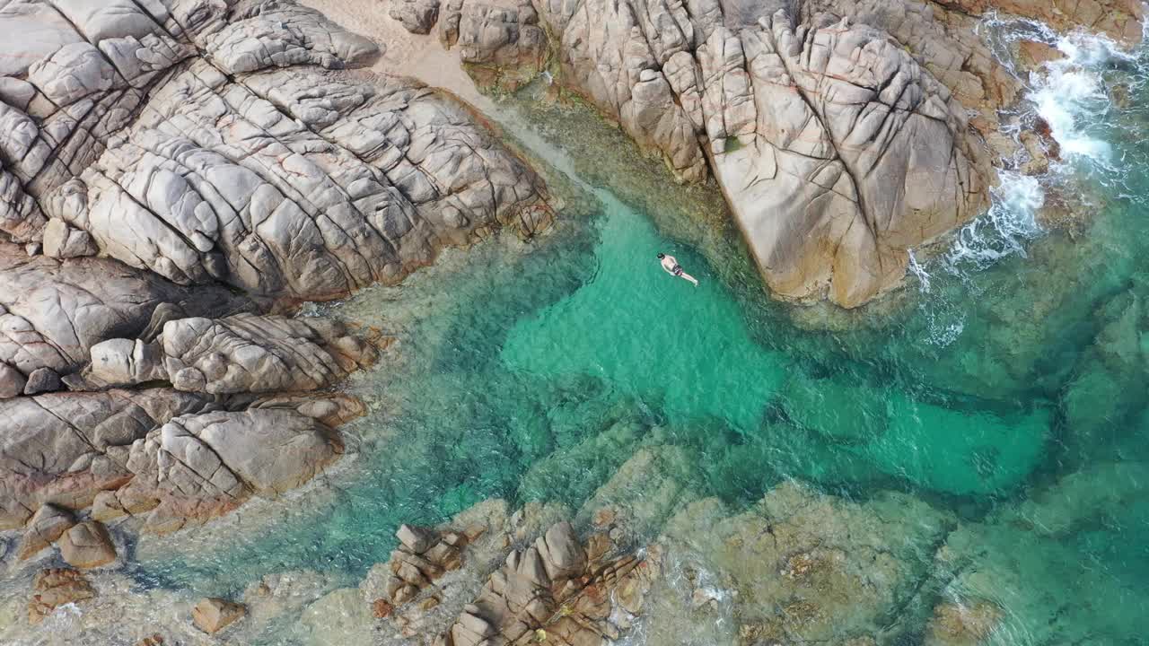 年轻的浮潜者在有岩石的海湾里游泳和潜水。视频下载