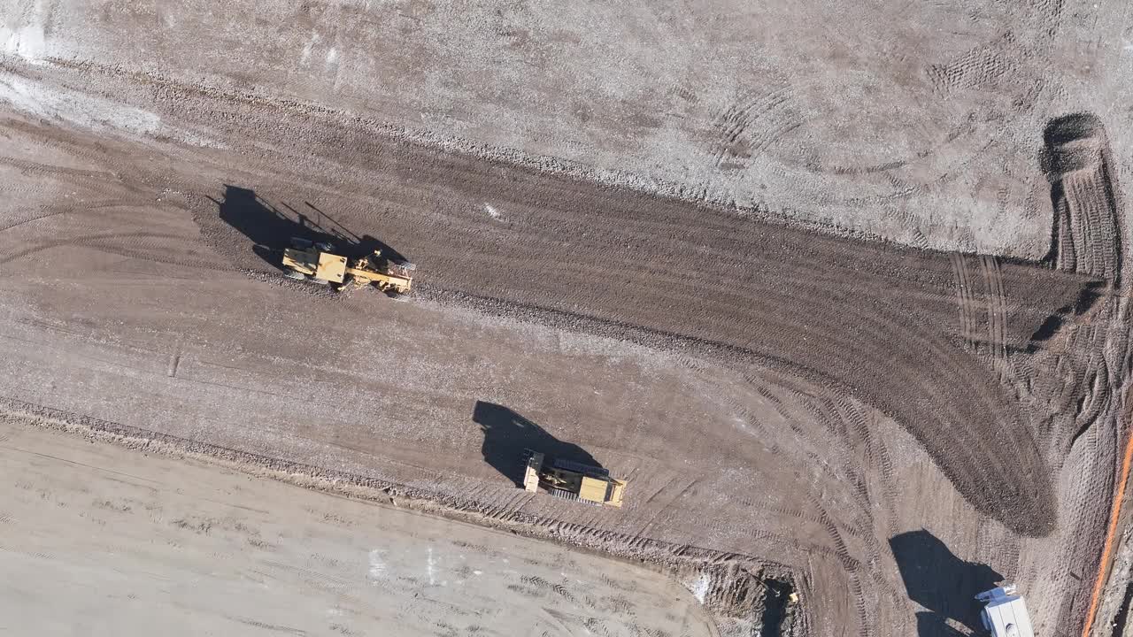 鸟瞰图:正在施工的黄色挖掘机、道路平地机、重土、在建筑工地工作的推土机视频素材