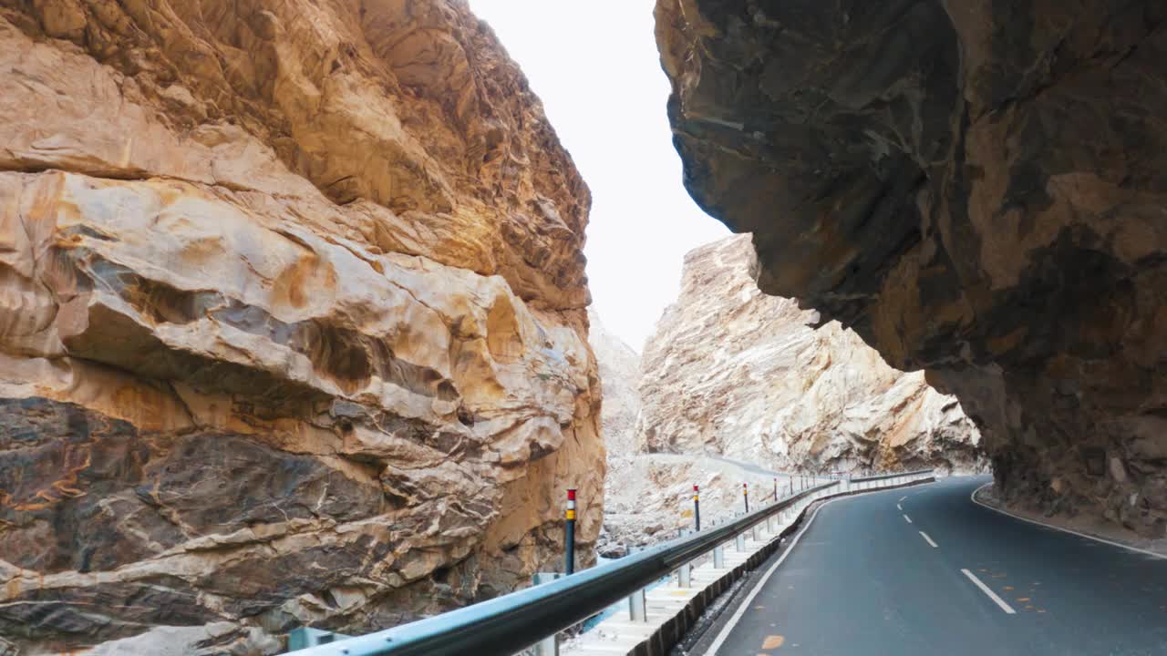 在印度斯皮蒂山谷附近的Khab sangam，一条蜿蜒的道路建在斯皮蒂河旁边的山上。POV镜头的汽车移动在柏油路在山区。公路旅行。视频素材