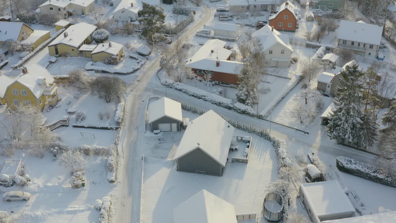 从空中俯瞰一座白雪覆盖的别墅，有古雅的房屋和蜿蜒的道路，这是由上升的无人机拍摄的视频下载