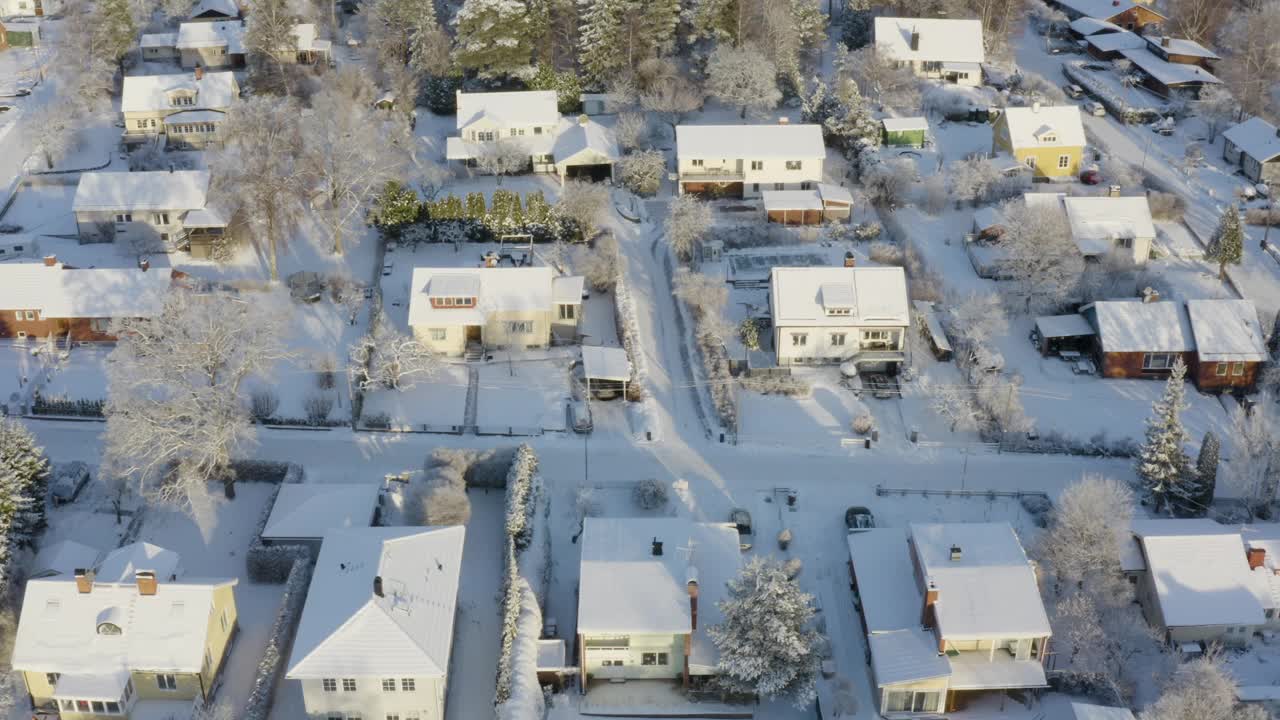 雪后，无人机拍摄的雪覆盖的住宅区里阳光明媚的别墅。视频下载