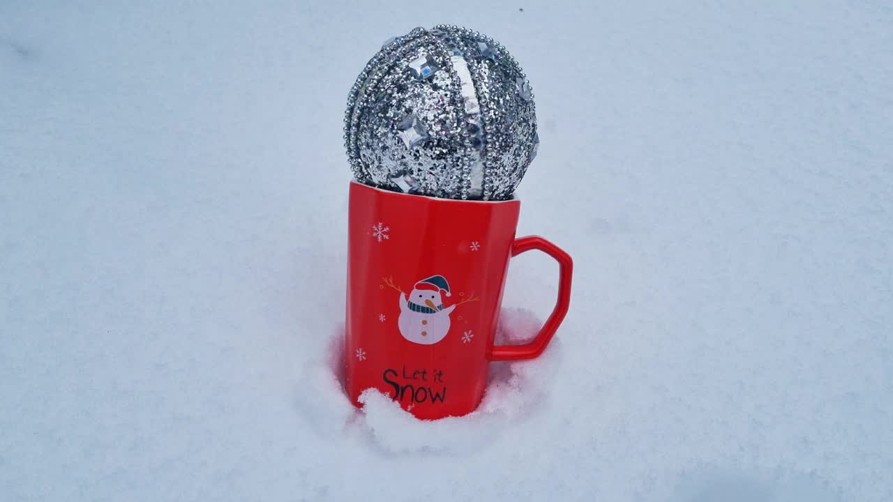 红色的马克杯上印有圣诞雪人的图案，让它站在雪地里，节日快乐视频下载