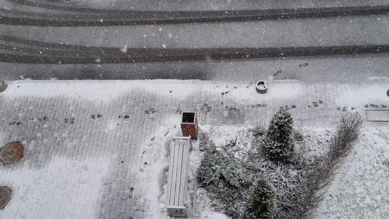 鸟瞰城市里的一条路，积雪覆盖的小路上的脚步声，街道上的初雪，冬天的奇迹，小镇上的大雪视频素材