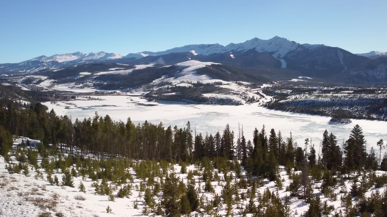 飞向冰封的湖面，背景是白雪覆盖的山脉视频素材