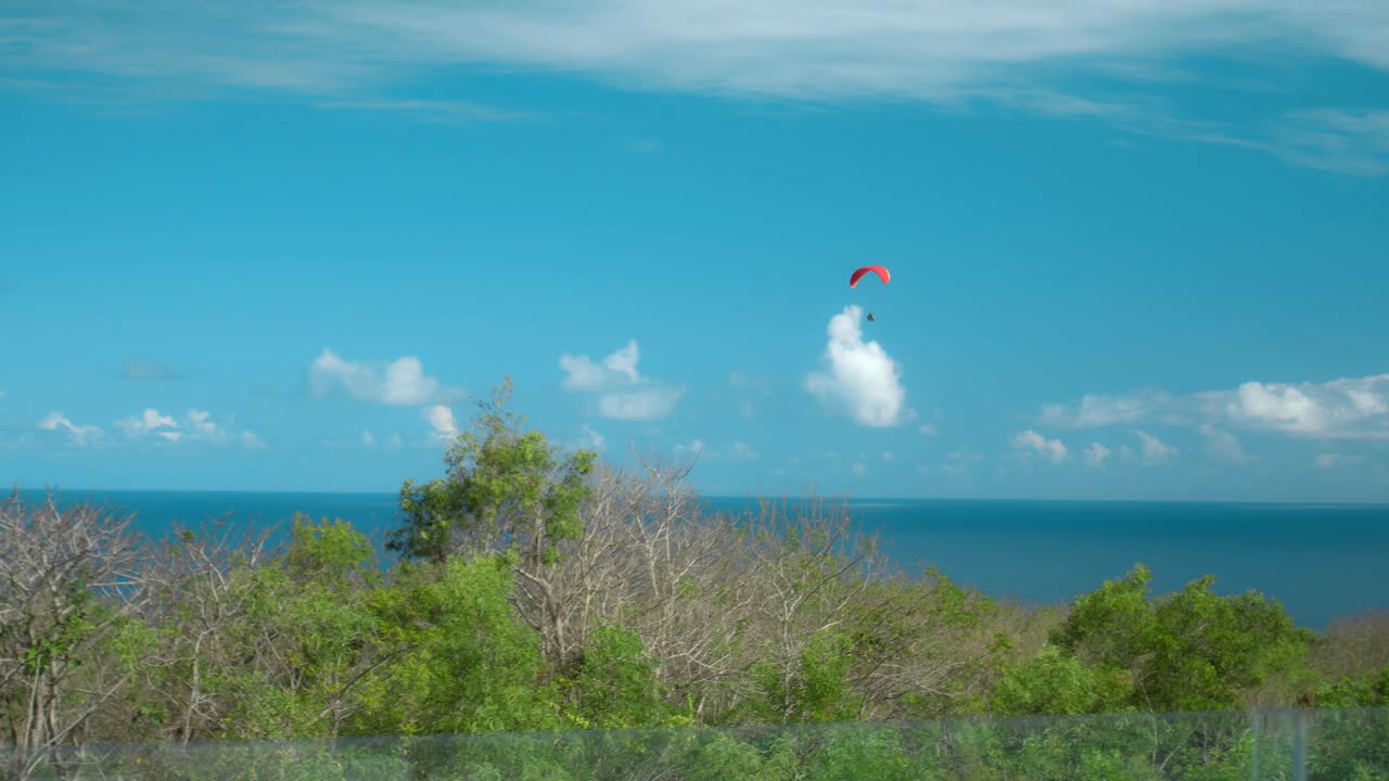 高空跳伞者在多云的天空中驾驶降落伞飞过海面视频下载