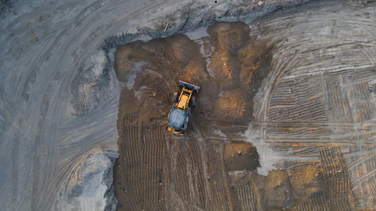 一辆拖拉机用铲斗铲平土堆。建设交通视频下载