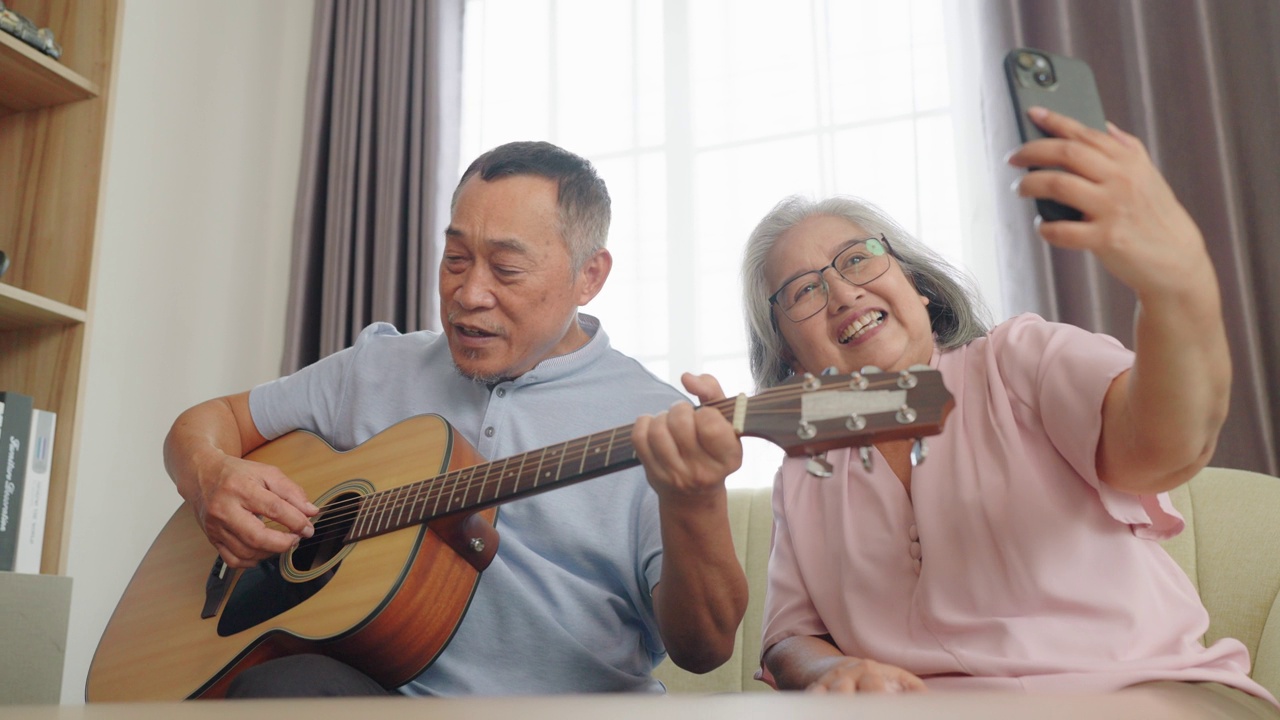 老年夫妇弹吉他，老年妇女用手机录音。视频素材