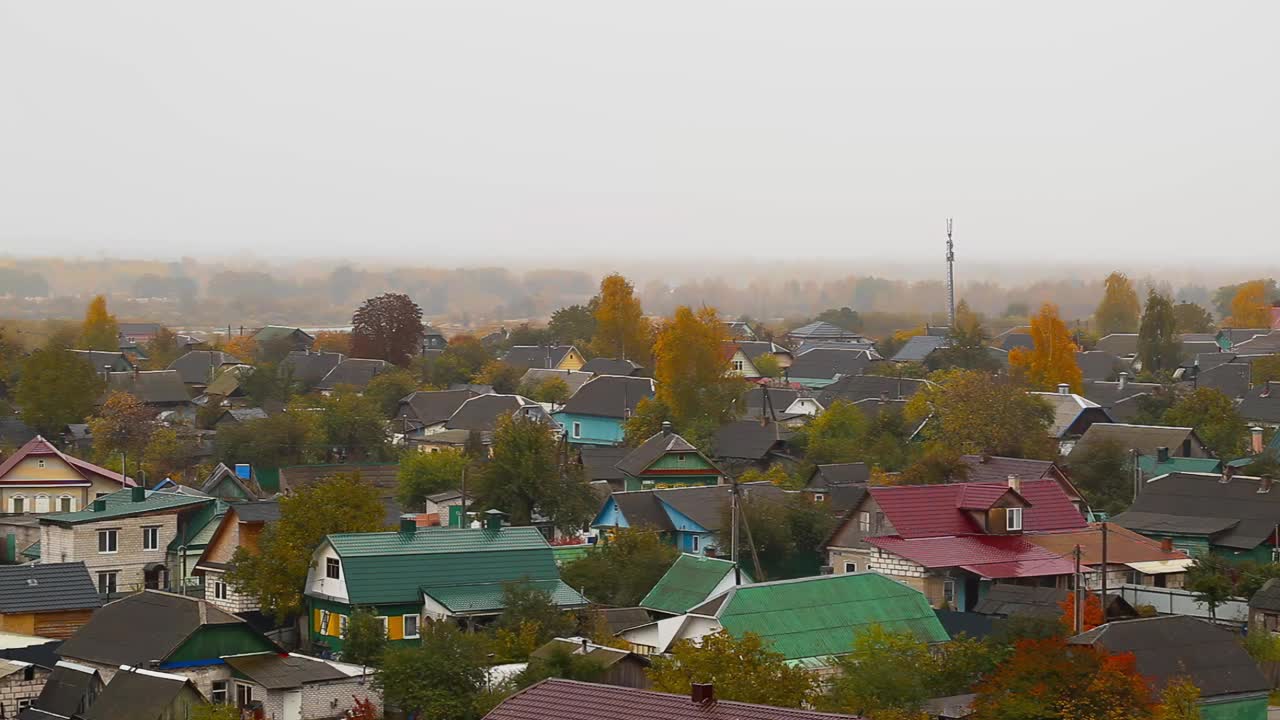 在秋天的雾和雨的背景下，私人住宅建筑和黄色树木的自然景观。秋天多云的天气。文本复制空间视频素材