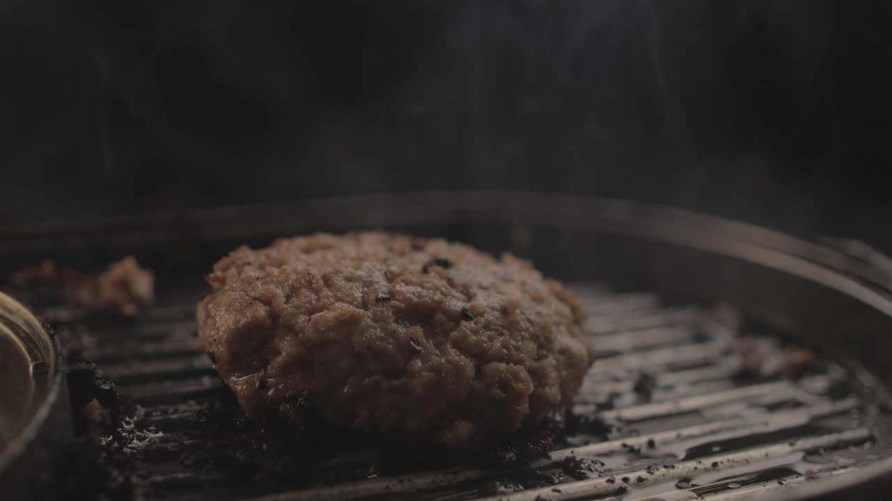 生牛肉或鸡肉汉堡在烤架上准备一个美味的汉堡三明治，然后带走，黑色背景和简单的光设置在Raw 4K上拍摄视频素材