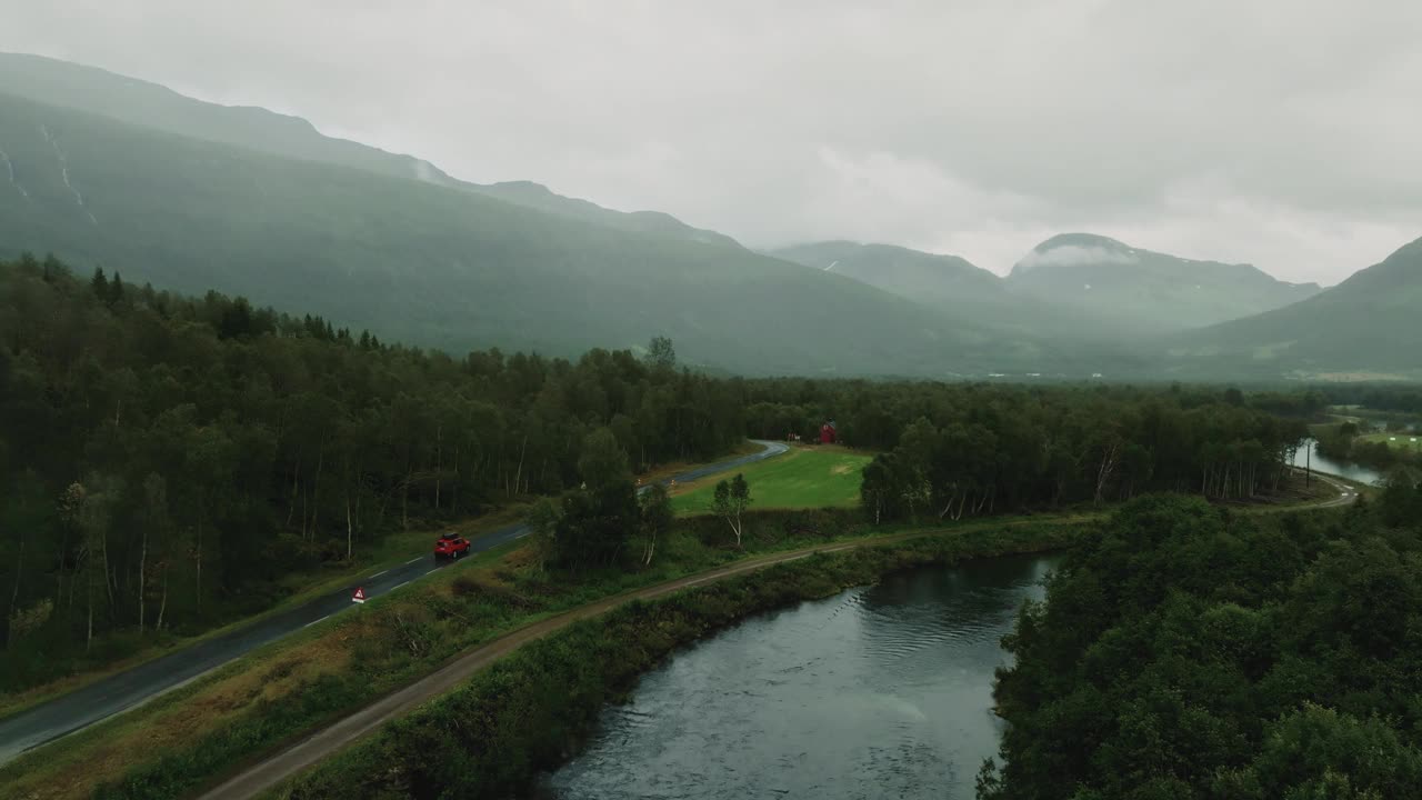 下雨天，红色SUV行驶在美丽的绿色斯堪的纳维亚乡村公路上的鸟瞰图视频素材