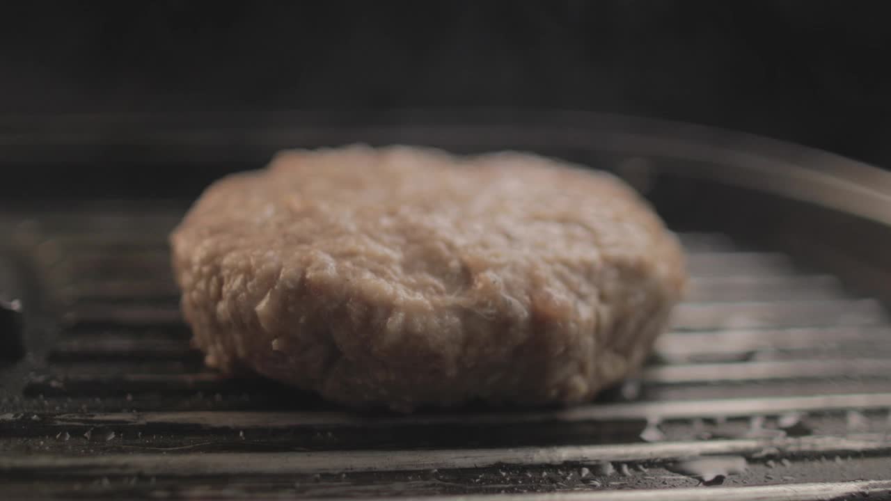 烤架上的牛肉或鸡肉汉堡正在准备美味的汉堡三明治，黑色背景和简单的光线设置在RAW 4K上拍摄视频素材