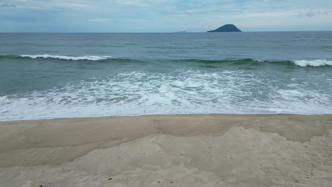 鸟瞰海岸的一个海滩，有波浪，岩石，多云的天空视频下载