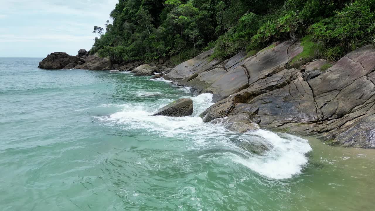 鸟瞰海岸的一个海滩，有波浪，岩石，多云的天空视频下载