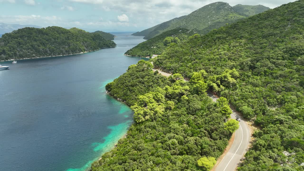 无人驾驶飞机拍摄了Mljet岛的丘陵景观，一辆汽车沿着沿海道路行驶。视频素材