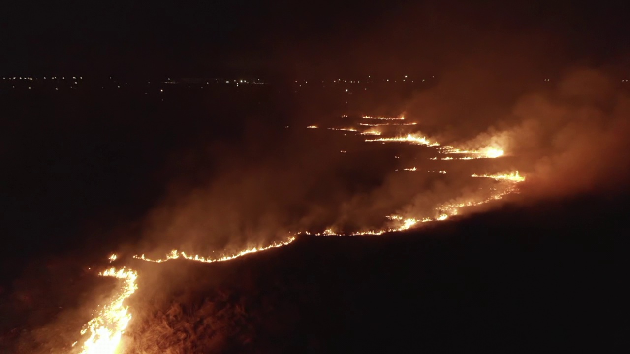 夜间的森林火灾，空中无人机的视角，背景是城市的灯光视频下载