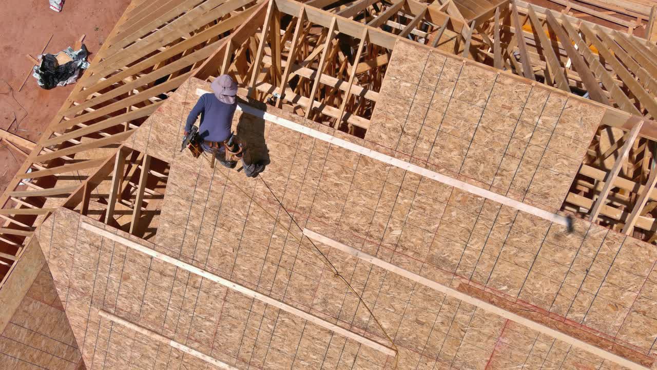 建筑工人将钉子钉在未来住宅屋顶的胶合板上视频素材