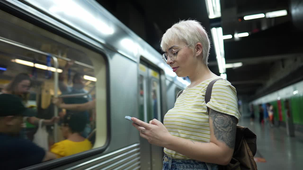 一名年轻女子在地铁站拿着手机的肖像视频素材