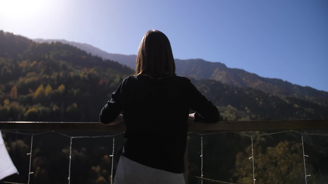 一个女孩站在阳台上欣赏美丽的自然景色视频素材