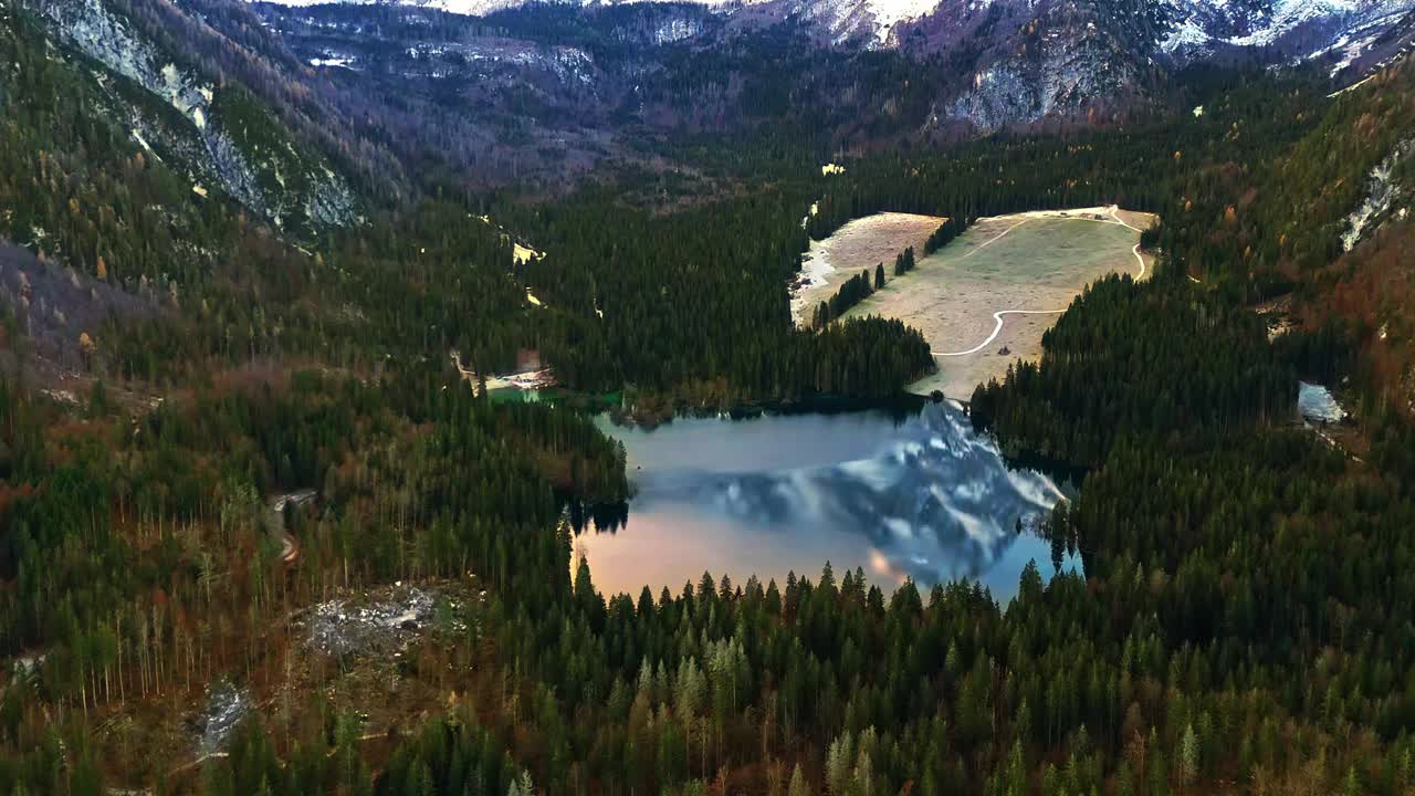 空中无人机拍摄的雪山映照在被茂密森林包围的高山小湖上视频素材