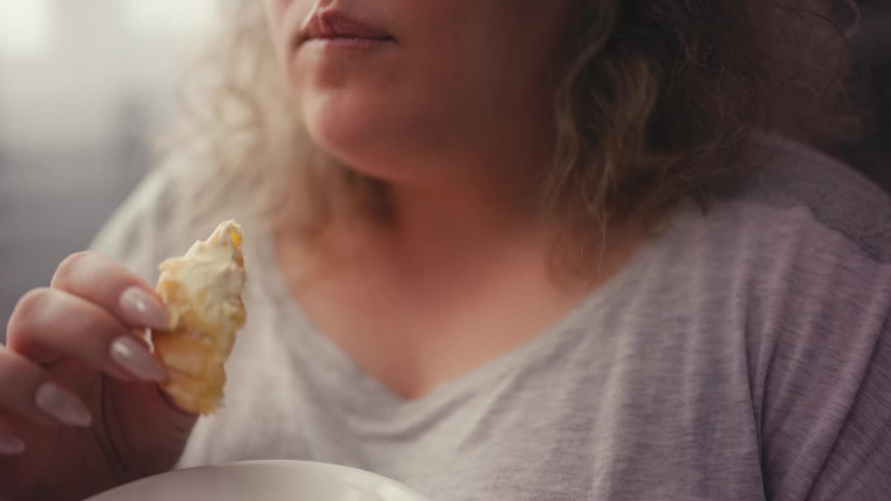 特写胖女人的嘴咬和咀嚼美味的蛋糕，饮食失调视频素材