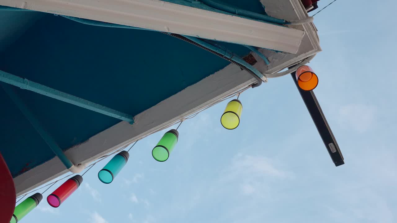 屋顶上五颜六色的灯笼。行动。屋顶上悬挂着五颜六色的玻璃灯泡。美丽的彩色灯光在蓝色的天空背景。视频素材